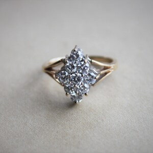 May include: A gold ring with a large cluster of clear diamonds set in a flower shape.