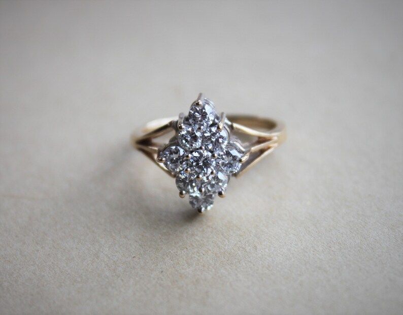 May include: A gold ring with a large cluster of clear diamonds set in a flower shape.