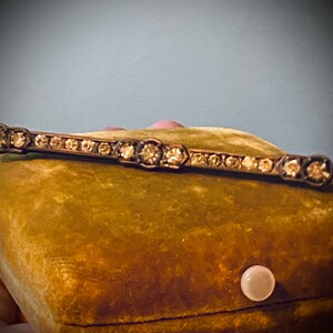 May include: A vintage silver bar pin with a row of clear rhinestones set in a geometric pattern.