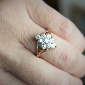 May include: A gold ring with a cluster of small diamonds set in a flower shape.