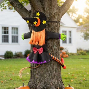 May include: A witch tree hugger decoration featuring a black pointed hat with yellow stars, bright orange hair, a black dress with a red and white polka dot bow, purple trim, green hands, and orange and black striped legs with red shoes.