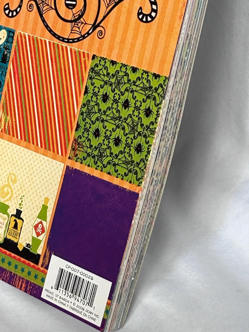 May include: A stack of decorative paper sheets featuring Halloween-themed patterns including orange stripes, green spider webs, and purple squares. A white barcode label with the text CP-007-00029 and PROVO, UT 84604 is visible on the bottom corner.