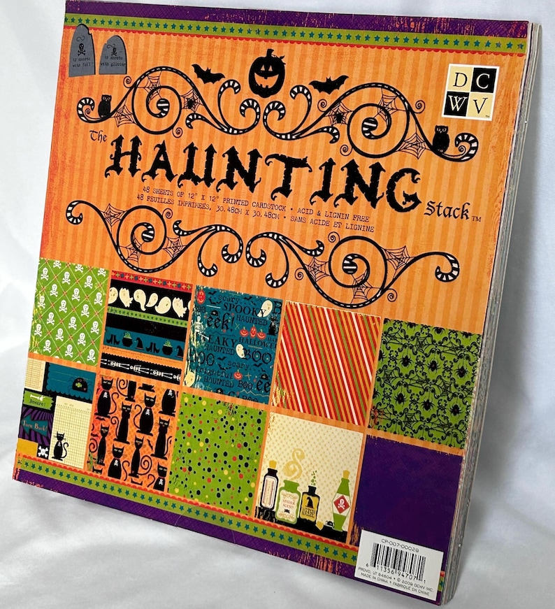 May include: A square paper pad titled The Haunting Stack featuring 48 sheets of 12 x 12 inch printed cardstock. The cover displays orange, purple, green, and black Halloween patterns including pumpkins, bats, cats, ghosts, and skulls.