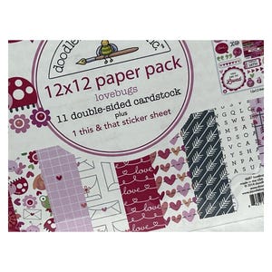 Op de afbeelding: Een 12x12 papierpakket getiteld lovebugs met 11 dubbelzijdige kartonnen vellen en 1 this & that stickervel. De verpakking heeft een witte achtergrond met diverse patronen, waaronder rode harten, roze enveloppen en zwarte pijlen.