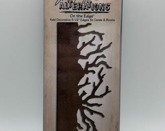 Op de afbeelding: Een Sizzix Tim Holtz Alterations On the Edge snijmal in een doorzichtige plastic verpakking. De mal heeft een solide rechthoekige basis met een grillige, takachtige rand ontworpen om decoratieve randen van 14 cm aan kaarten en boeken toe te voegen.