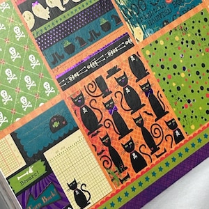 May include: A decorative paper sheet featuring a collage of Halloween-themed patterns including black cats with skull collars, white ghosts, green skull prints, and text elements like Beware and Turn Back in orange, green, purple, and black.