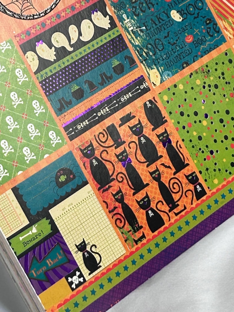 May include: A decorative paper sheet featuring a collage of Halloween-themed patterns including black cats with skull collars, white ghosts, green skull prints, and text elements like Beware and Turn Back in orange, green, purple, and black.