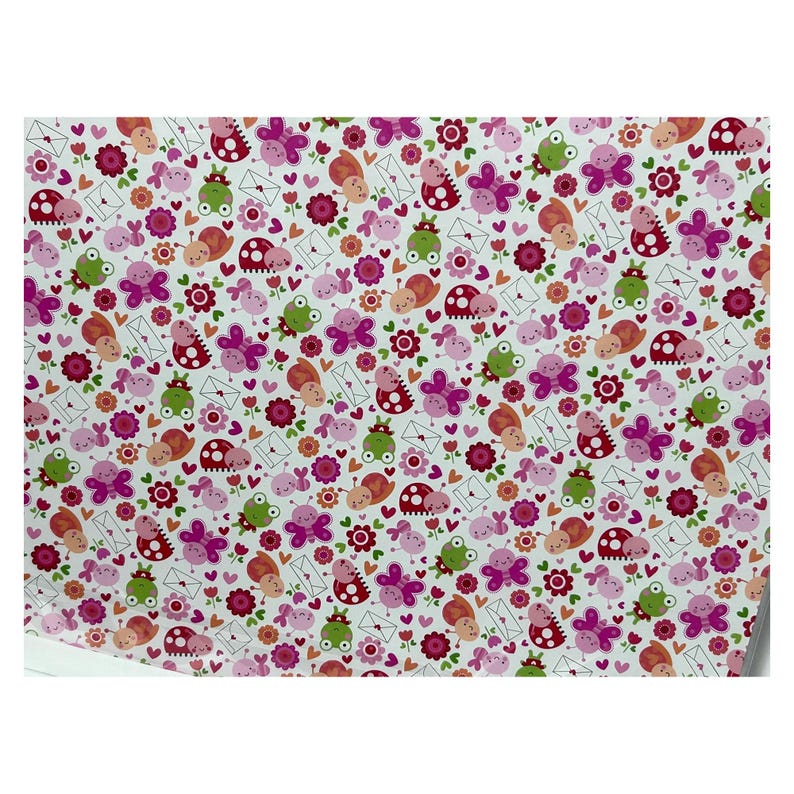 Op de afbeelding: Een wit vel inpakpapier met een herhalend patroon van cartoonkikkers, roze vlinders, lieveheersbeestjes, slakken, kleine rode bloemen en witte enveloppen met kleine rode hartjes verspreid over het oppervlak in een kleurrijk ontwerp.