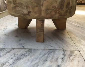 Può includere: Un grande tagliere rotondo in legno con finitura in legno naturale. Il tagliere è sostenuto da tre gambe corte e robuste.