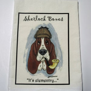 May include: A white kitchen towel with a cartoon illustration of a basset hound wearing a detective hat and smoking a pipe. The text "Sherlock Bones" and "It's elementry..." are printed on the towel.