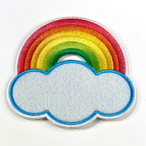 May include: A rainbow-colored felt patch with a white cloud underneath. The rainbow has red, orange, yellow, green, blue, and purple stripes.