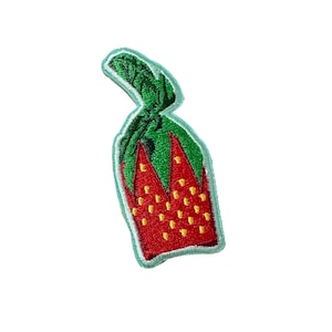 May include: A red and green embroidered patch of a strawberry with yellow seeds.