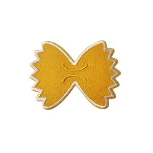 May include: A yellow farfalle pasta patch with white stitching. The embroidered patch features a detailed design of the pasta shape, with a textured appearance. The patch is designed to be ironed on or sewn onto fabric.