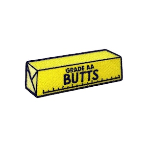 May include: Yellow stick of butter with the text "GRADE AA BUTTS" printed on it.
