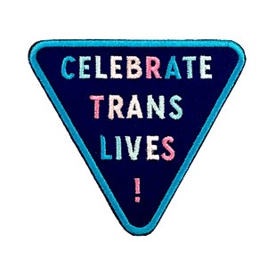 May include: A blue triangle patch with the text "CELEBRATE TRANS LIVES!" in pink, blue, and white lettering.