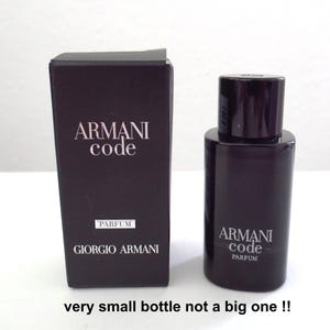 Op de afbeelding: Een donkerpaarse parfumfles en bijpassende doos. De doos en fles zijn beide voorzien van de tekst "ARMANI Code" in witte letters. De doos bevat ook "PARFUM" en "GIORGIO ARMANI". De fles is cilindrisch met een donkere dop.