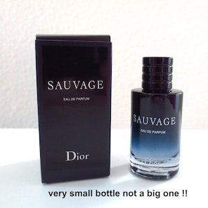 Könnte beinhalten: Eine schwarze Parfümbox und Flasche "Sauvage" Eau de Parfum von Dior. Die Flasche hat ein blau-schwarzes Farbverlauf-Design. Auf der Box und der Flasche stehen Markenname und Produktdetails.