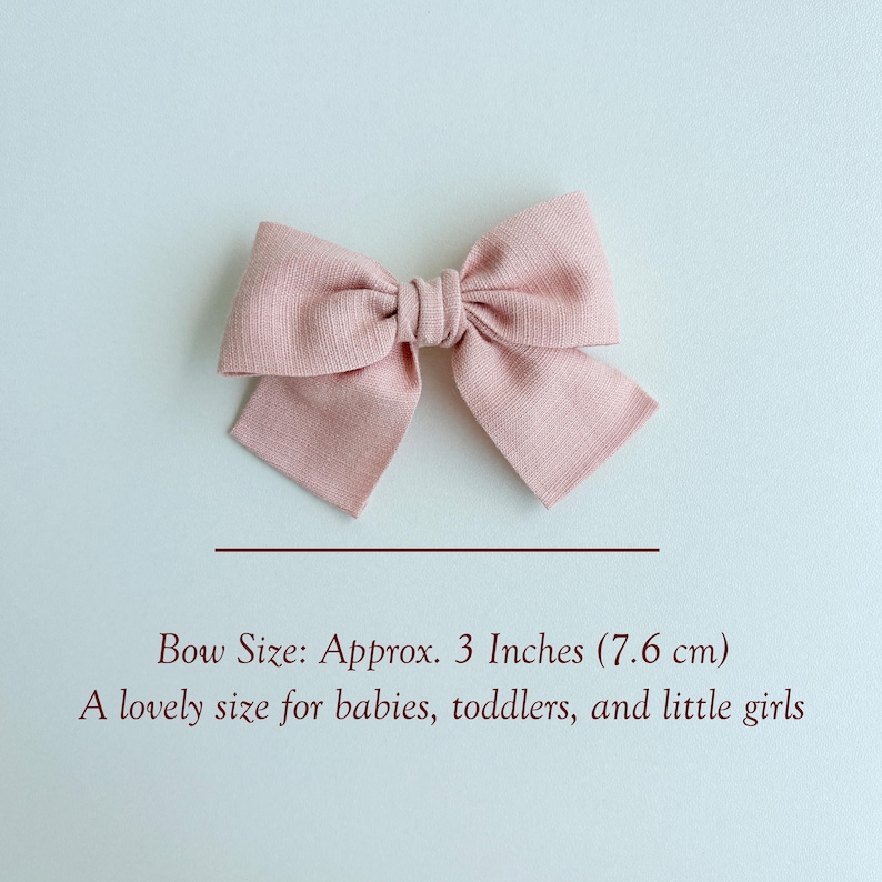 Peut inclure: Un n&oelig;ud pour cheveux en tissu rose poudr&eacute; avec une finition textur&eacute;e. Le n&oelig;ud pr&eacute;sente un n&oelig;ud central et deux boucles sym&eacute;triques. Le texte indique : Bow Size: Approx. 3 Inches (7,6 cm). A lovely size for babies, toddlers, and little girls.