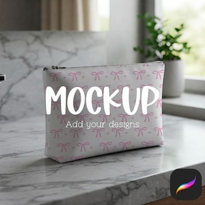 Puede incluir: Un neceser blanco con un estampado de lazos rosas y la palabra "MOCKUP" en letras blancas grandes. El texto "Add your designs" está debajo de la palabra "MOCKUP". El neceser tiene una cremallera plateada y está sobre una superficie de mármol.