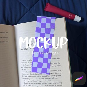 Può includere: Un segnalibro a scacchi viola e bianco è posto in un libro aperto. Un tubetto di lucidalabbra rosso è appoggiato sulle pagine del libro. La parola "MOCKUP" è scritta sull'immagine, con il testo "Add your designs" sotto.