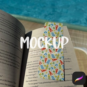 May include: A colorful bookmark with a summer theme, featuring red lobsters, blue beach towels, yellow lemons, and bottles on a white background. The bookmark is placed in an open book.