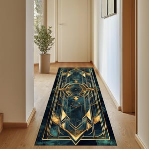 May include: A teal and gold geometric patterned runner rug with a central eye design. The rug is laid out in a hallway with wooden floors.