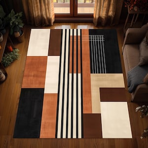 May include: A rectangular area rug with a geometric design. The rug features blocks of black, cream, brown, and rust-colored sections. Vertical stripes in black and cream are also present. The rug is placed on a hardwood floor.