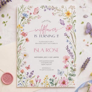May include: A white birthday invitation card featuring a watercolor floral border with pink, yellow, blue, and purple wildflowers and butterflies. The text reads: Our little wildflower is turning 1! Isla Rose, Saturday, July 25 at 2:00 PM.