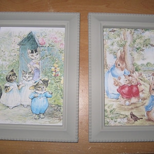 May include: Two framed illustrations, one depicting a group of cats in a garden setting, the other showing a family of rabbits in a woodland scene.