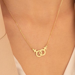 May include: A gold necklace with a pendant featuring two interlocking female symbols.