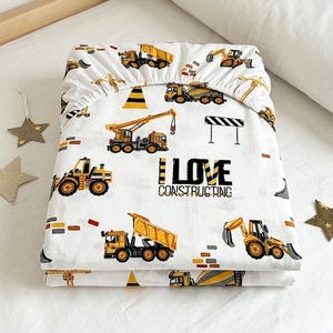May include: White fitted sheet with a construction theme. The sheet features yellow and black construction vehicles, including excavators, dump trucks, and cranes. The text "I LOVE CONSTRUCTING" is also printed on the sheet.