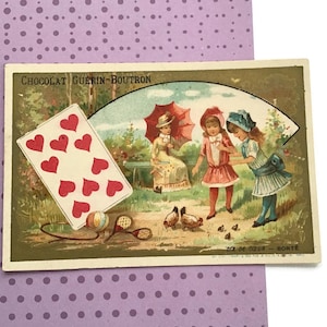 以下が含まれることがあります： 庭のシーン、子供たち、鶏、ハートのトランプが描かれたヴィンテージポストカード。 ポストカードには「Chocolat Guerin-Boutron」と「Dix de Coeur - Borte」の文字が記載されています。 白い水玉模様の紫色の背景に設定されています。