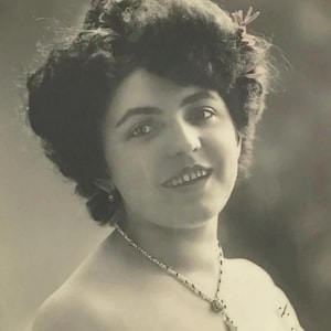 Antica cartolina francese – Donna sorridente con scialle di pizzo e collana a croce, ritratto dei primi anni del 1900