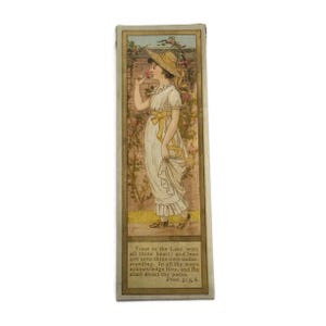 Könnte beinhalten: Vintage Lesezeichen mit einer Illustration einer Frau in einem weißen Kleid und Strohhut, die an einer Rose riecht. Der Hintergrund zeigt eine Backsteinmauer und Blumen. Der Text unten lautet "Vertraue dem Herrn..." und ein Bibelvers.