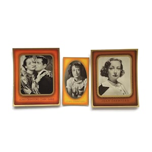 May include: Three vintage Joan Crawford trading cards. The cards have a gold border and feature black and white images of the actress. One card shows Crawford with Clark Gable. The text "JOAN CRAWFORD" is printed on the cards.