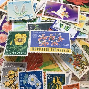 Puede incluir: Una colección de sellos postales antiguos con diversas ilustraciones botánicas, incluyendo flores y plantas de países como Líbano, Bután, Malasia, Indonesia, Suiza, Australia y Japón, con texto y denominaciones claramente visibles.