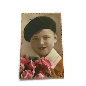 Antieke gekleurde ansichtkaart – lachende jongen met baret en bloemen, begin jaren 1900