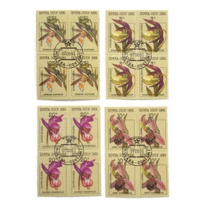 Può includere: Una collezione di francobolli vintage dell'URSS, con illustrazioni floreali. I francobolli presentano varie denominazioni e testo in cirillico, con un timbro postale centrale. I francobolli sono in tonalità di giallo, verde, viola e rosa.
