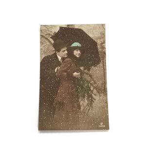 Postal antigua con escena nevada: Pareja romántica bajo un paraguas – Tarjeta fotográfica francesa de 1912