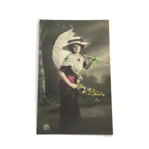 Antieke Franse ansichtkaart – dame met parasol en bloemen – handgekleurd 'Bonne Fête', 1912