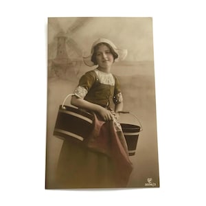 Postal antigua de una joven holandesa: escena de molino de viento coloreada a mano en sepia, con traje tradicional.