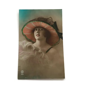 Ręcznie barwiona prawdziwa pocztówka fotograficzna – Uśmiechnięta kobieta w szerokim kapeluszu, początek lat 1900.
