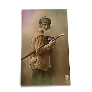 Vintage ansichtkaart – Stijlvolle vrouw met wandelstok en bloemen – handgekleurde RPPC – Belgian Fashion jaren 1920