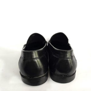 May include: A pair of black leather loafers with a simple design. The shoes have a rounded toe and a low heel.