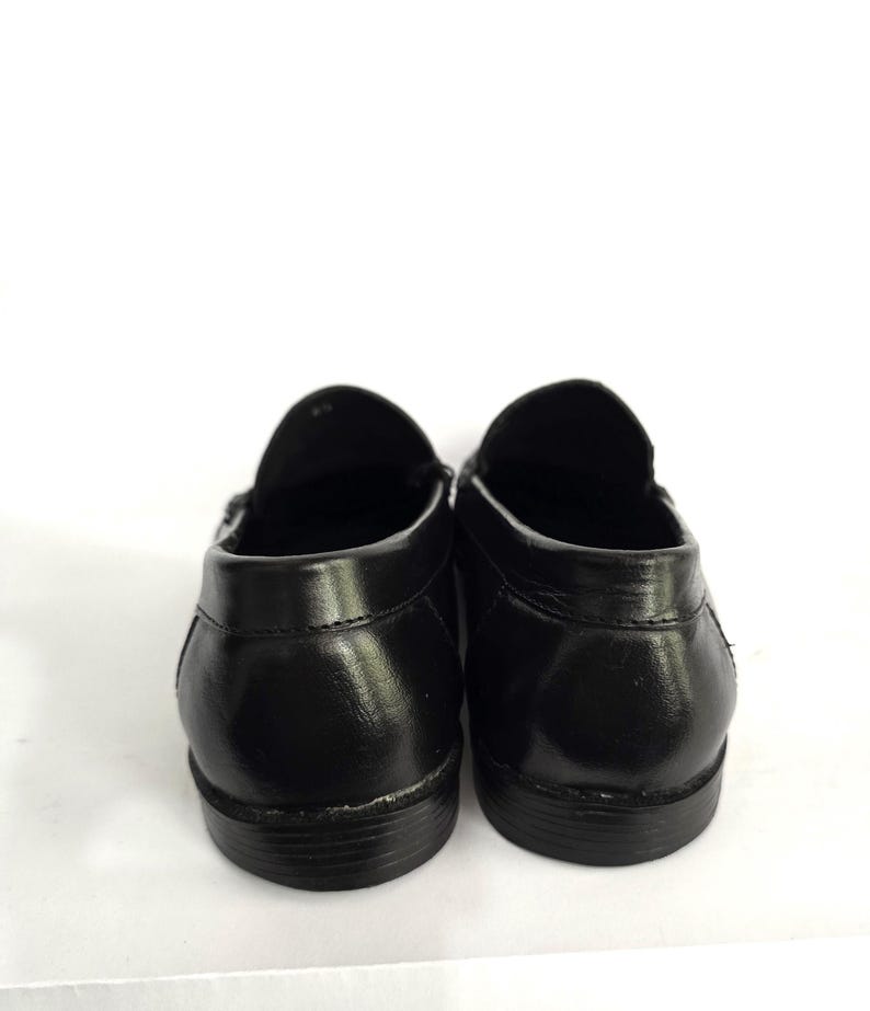 May include: A pair of black leather loafers with a simple design. The shoes have a rounded toe and a low heel.