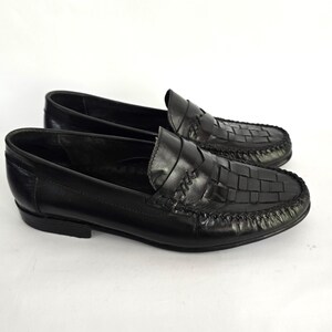 May include: A pair of black leather loafers with a woven pattern. The loafers have a pointed toe and a low heel.