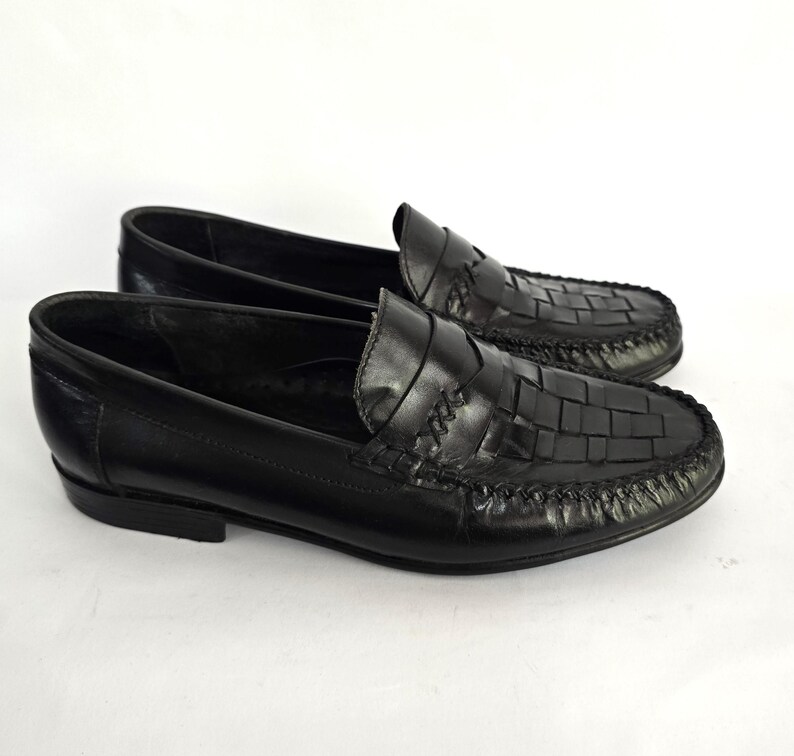 May include: A pair of black leather loafers with a woven pattern. The loafers have a pointed toe and a low heel.