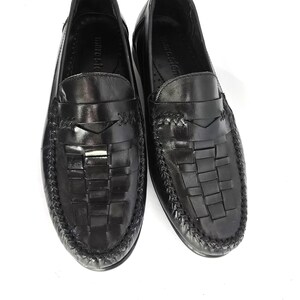 May include: Black leather loafers with a woven design and a leather strap across the top. The loafers have a black leather sole and a black leather lining.