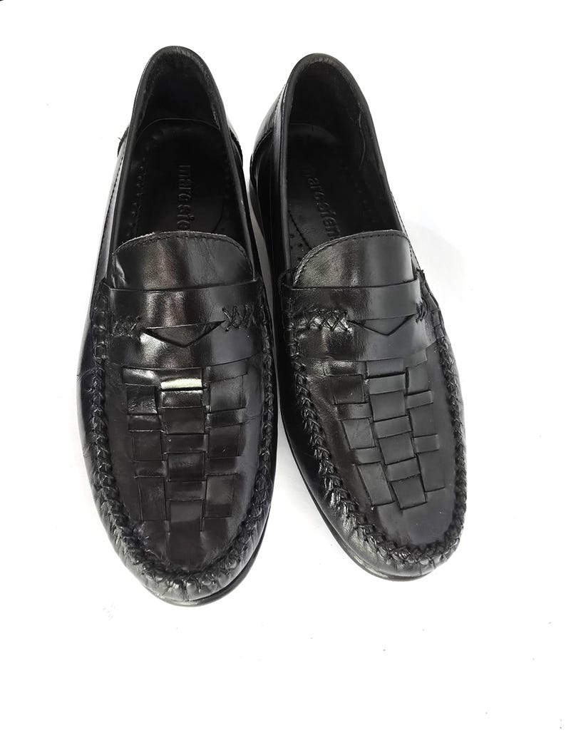 May include: Black leather loafers with a woven design and a leather strap across the top. The loafers have a black leather sole and a black leather lining.