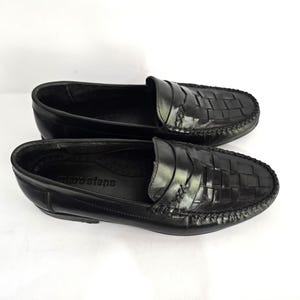 May include: A pair of black leather loafers with a woven pattern. The loafers have a moc toe design and a leather sole. The brand name "Marsten's" is visible on the insole.